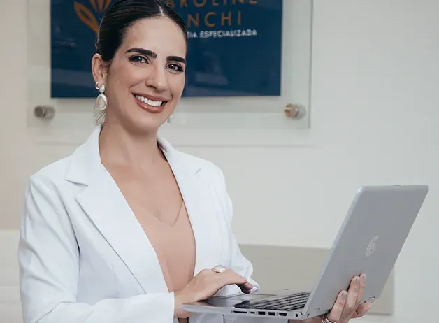 Dra. Caroline Bianchi com o notebook, na clínica